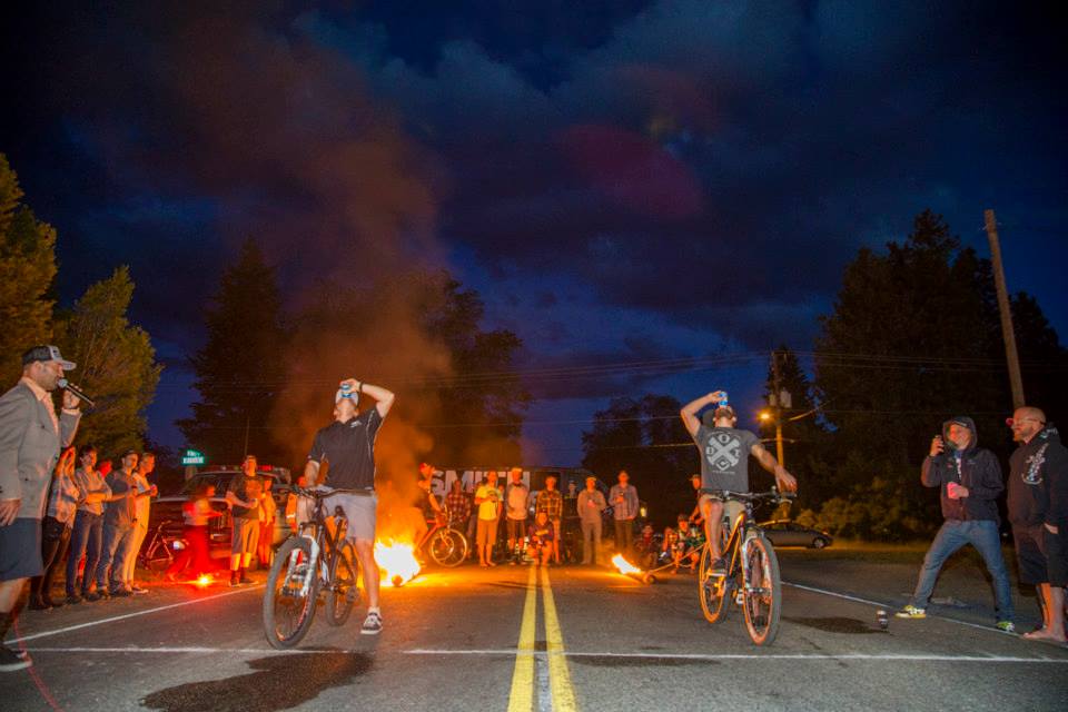 Shotgun challenge! Two riders prepare to drag the flaming logs behind them but must first completely drain a cold one.